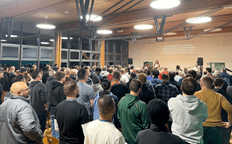 gran grupo de hombres frente a un escenario de músicos